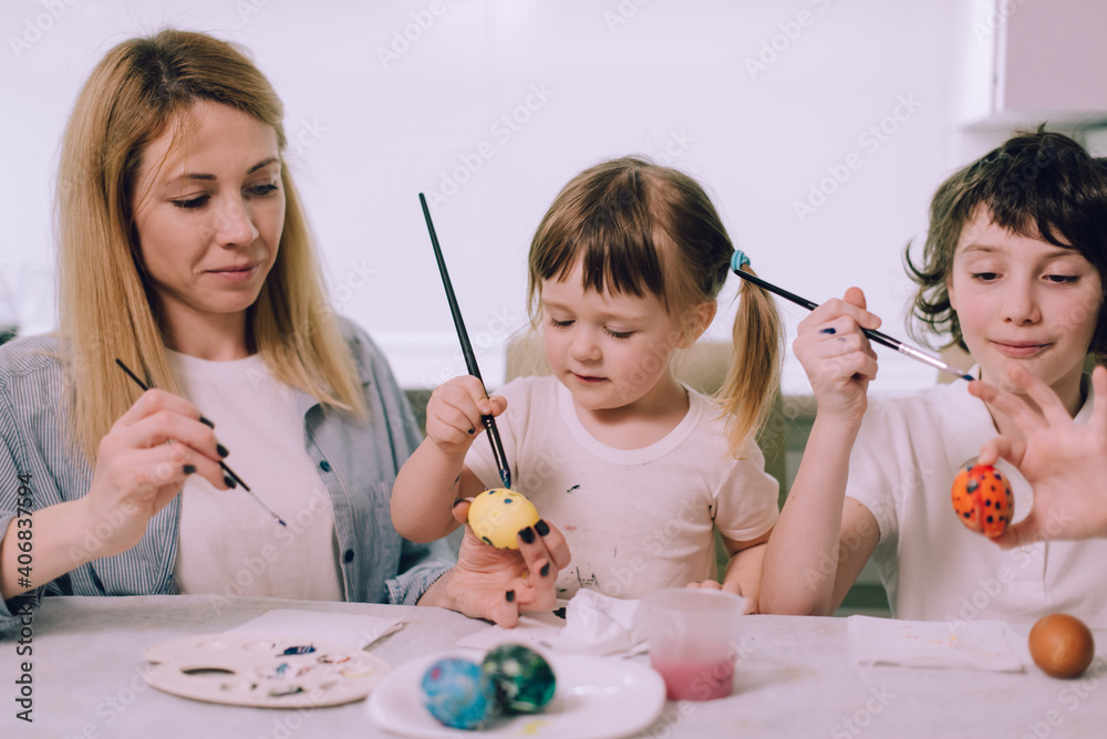 Preparing for Easter. The family is painting Easter eggs at home in the kitchen. Mom teaches her daughters to draw. Medium shot. Preparing for Easter. The family is painting Easter eggs at home in the kitchen. Mom teaches her daughters to draw. Medium shot.