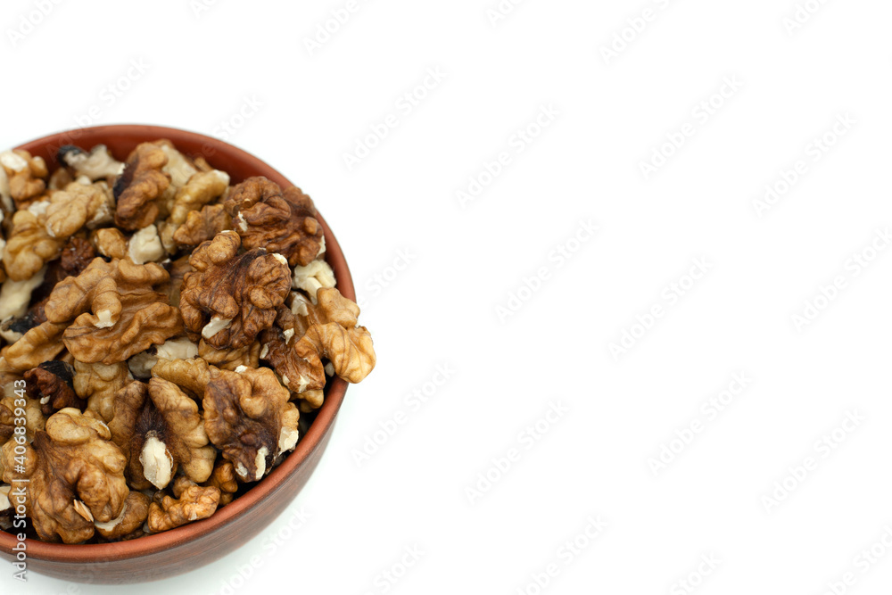 Peeled walnuts in a clay plate. Close-up. Isolated on white. Top view.