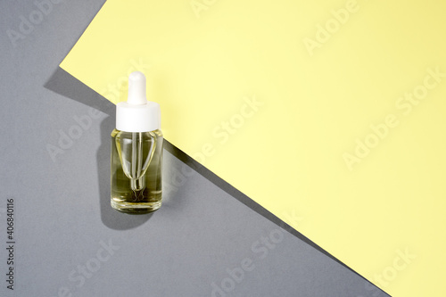flat lay cosmetic transparent bottle with oil on grey and yellow color paper background. High quality photo