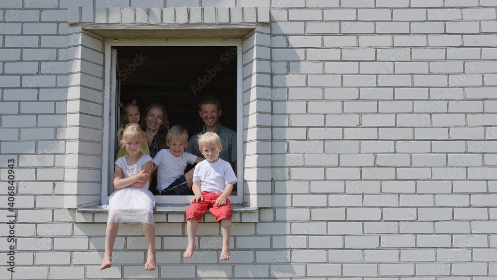 A large large family poses from the window of their home. A large large family poses from the window of their home.
