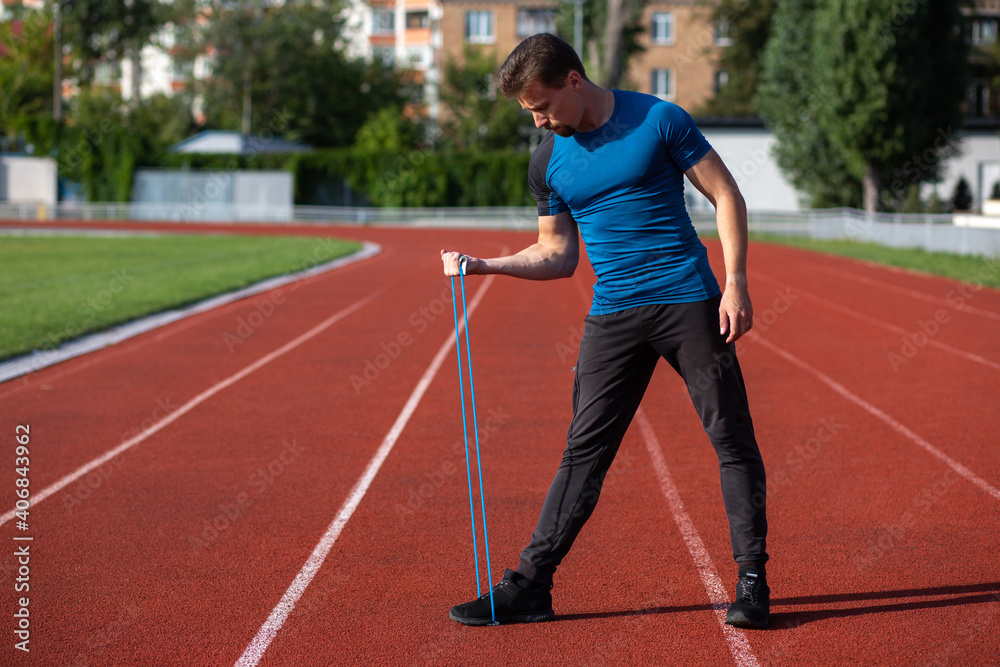 Sporty guy having workout with rubber band outside Sporty guy having workout with rubber band outside