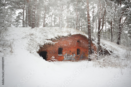 An old abandoned red brick military pillbox in the middle of the snow-covered forest. Latvia, Europe. Landmarks, architecture. History, past, war, conflict, fortification, protection themes photo