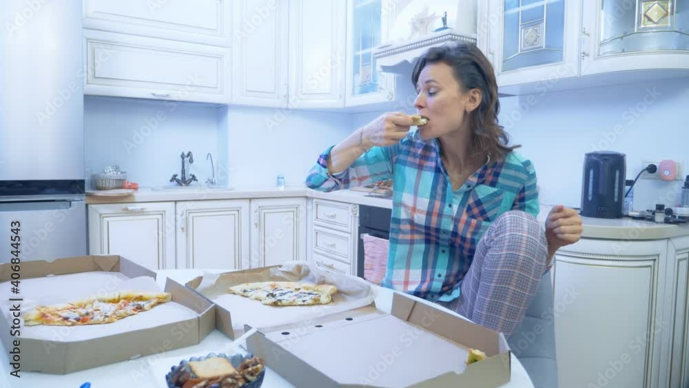 cheerful funny woman eating pizza out of the box at home in the kitchen. cheerful funny woman eating pizza out of the box at home in the kitchen.