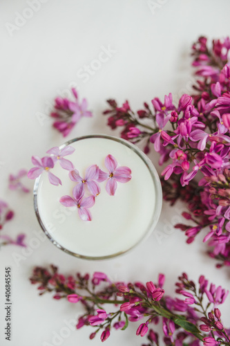 Lilac flowers on the table and in a glass of milk. White background. Free space for an inscription.