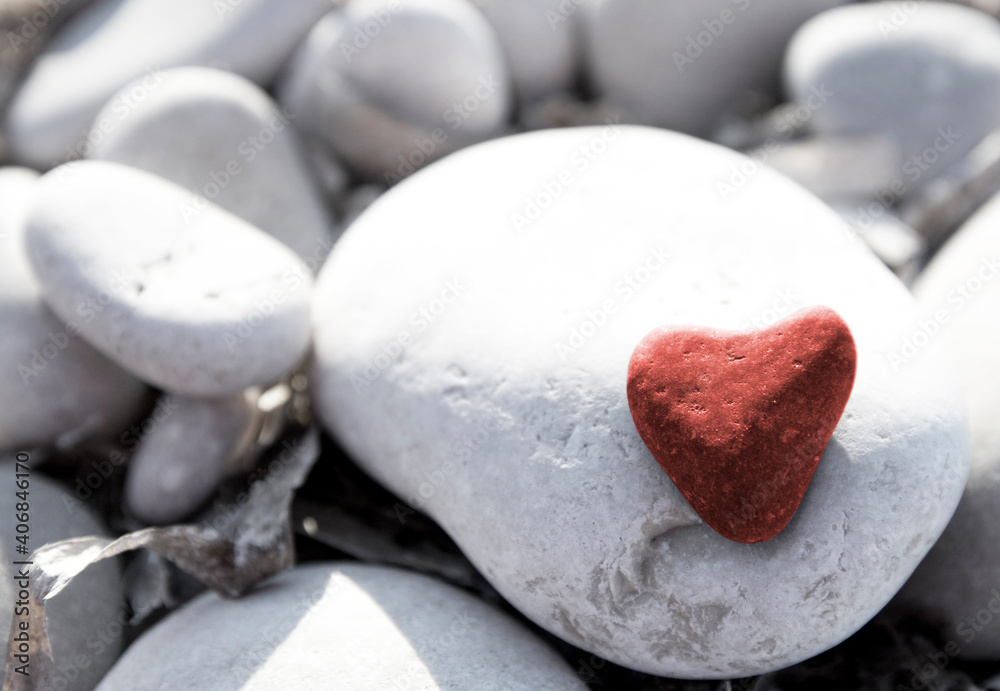 Obraz premium Red stone heart among river or sea pebble stones, Valentine's Day, perfect love