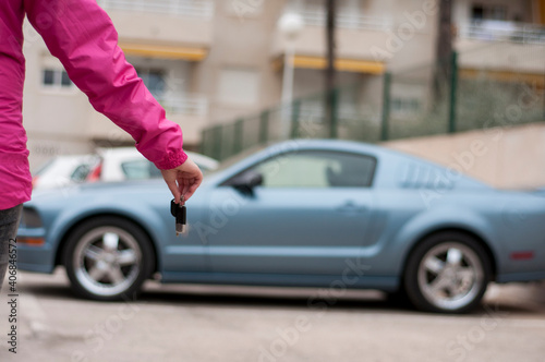 Woman's hand holding modern car keys ready for rental - Concept of transportation with automobile second hand sale and trade