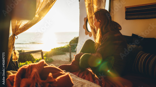 Chica pelirroja en una furgoneta camper camperizada en una zona costera de playa al atardecer leyendo y escribiendo con estilo libre hippie photo