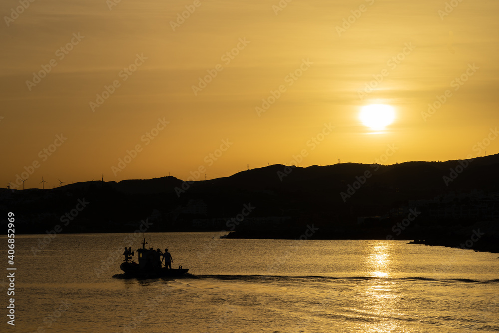 A photo of sunset in the coast with a fishing boat, at the end of the day