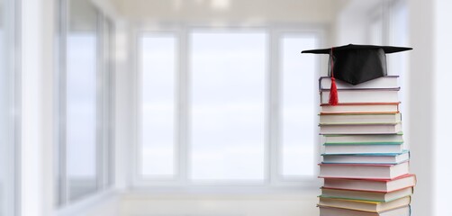 Stack school books with black graduation hat