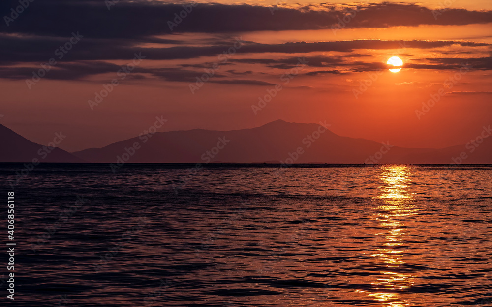 orange fiery sundown sky with some clouds over calm sea, nature background.