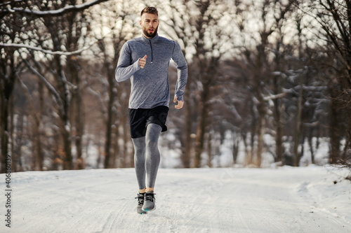 Runner jogging in nature at winter on snowy weather. Winter fitness, snowy weather, chilly