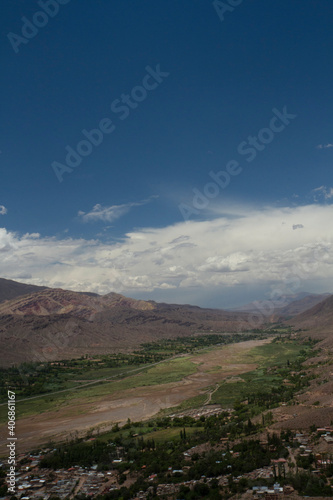 Idyllic landscape with beautiful sky. View of Humahuaca ravine, brown mountains, Andes desert, green valley and Tilcara village in Jujuy, Argentina.