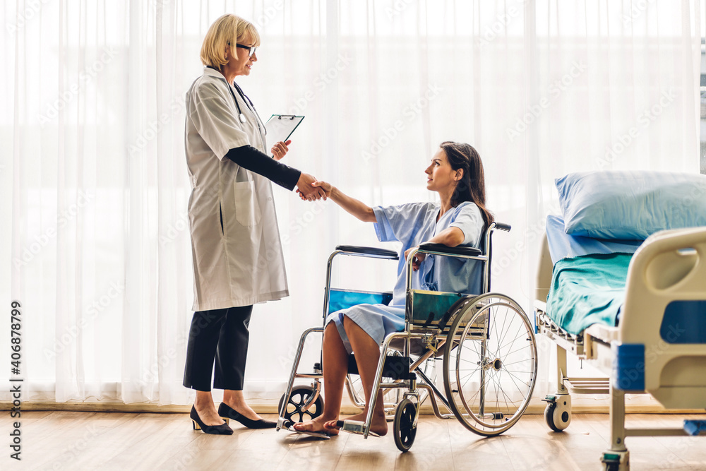 Senior woman doctor wearing uniform with stethoscope consulting and holding hand and handshake with patient reassuring with care in hospital.healthcare and medicine trust concept Senior woman doctor wearing uniform with stethoscope consulting and holding hand and handshake with patient reassuring with care in hospital.healthcare and medicine trust concept