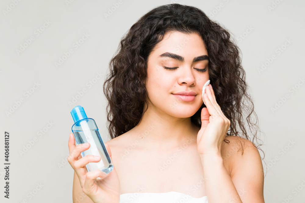 Young woman removing her makeup with a cleanser Young woman removing her makeup with a cleanser