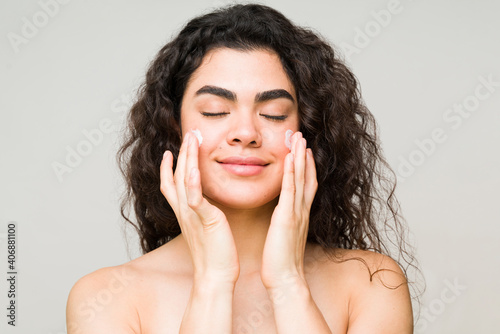 Pretty woman putting sunscreen on her face photo