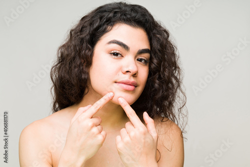 Young woman checking her face for acne or marks