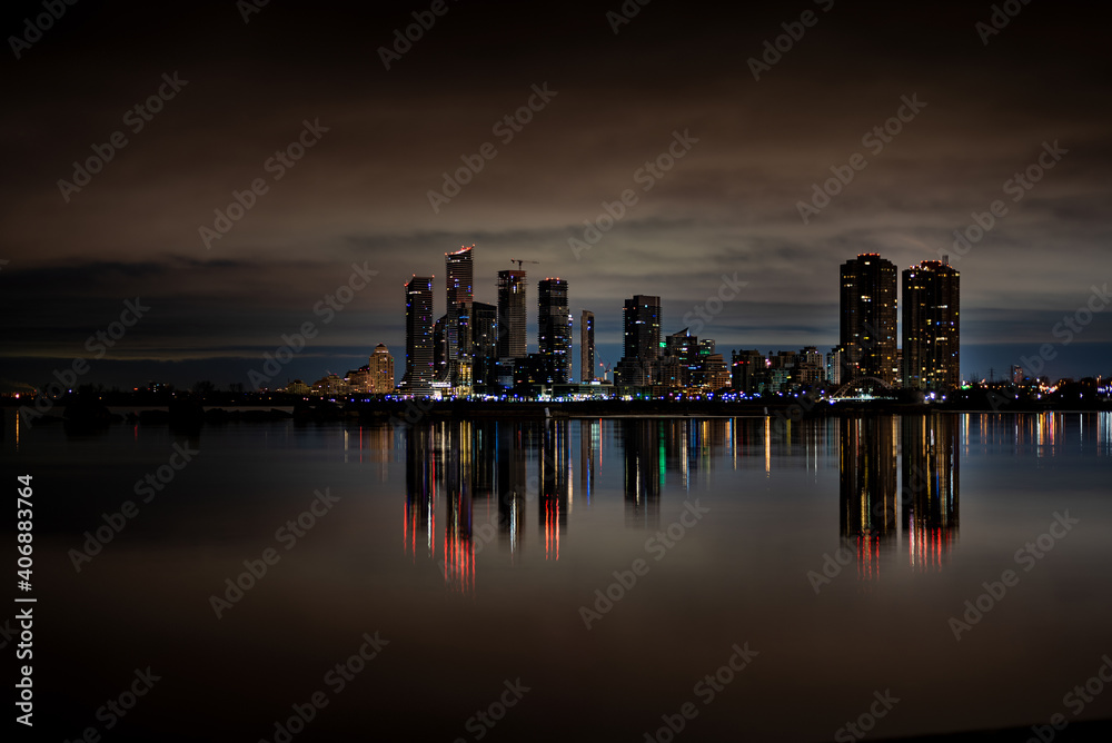 City skyline across the water at night with reflection City skyline across the water at night with reflection