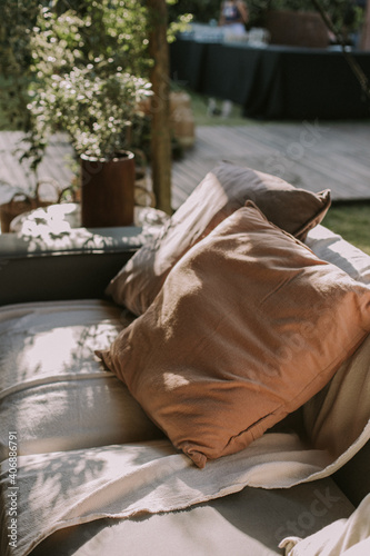 Armchair with two cushions and a white fabric with flowers in the background.