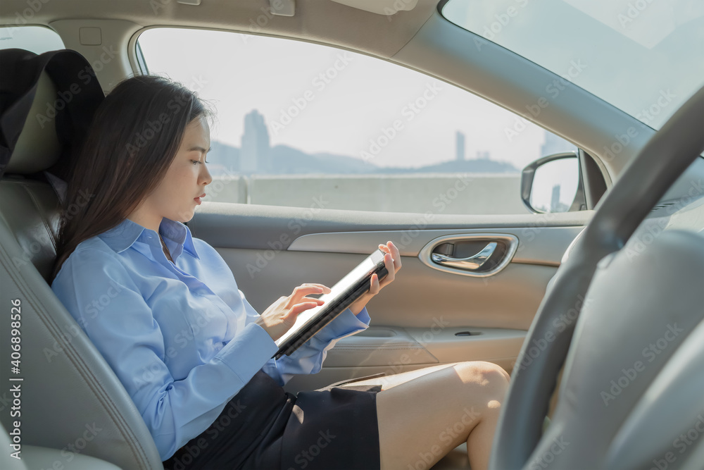 Businesswoman inside a car using a tablet for working.