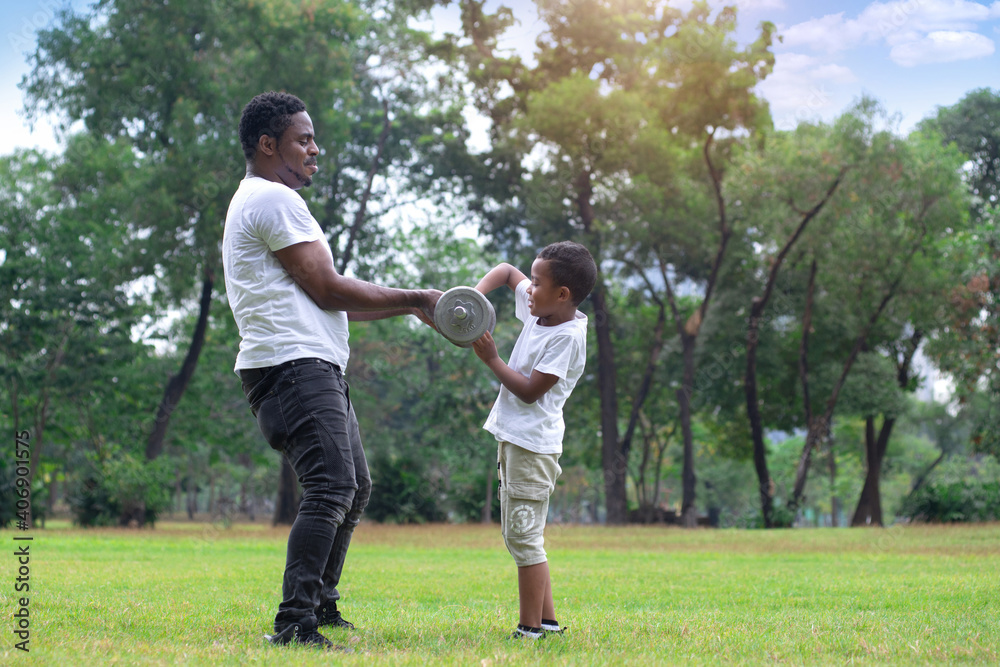 African father teaching his son exercising with dumbbells in green park, spend time together at outdoor park, Father's day