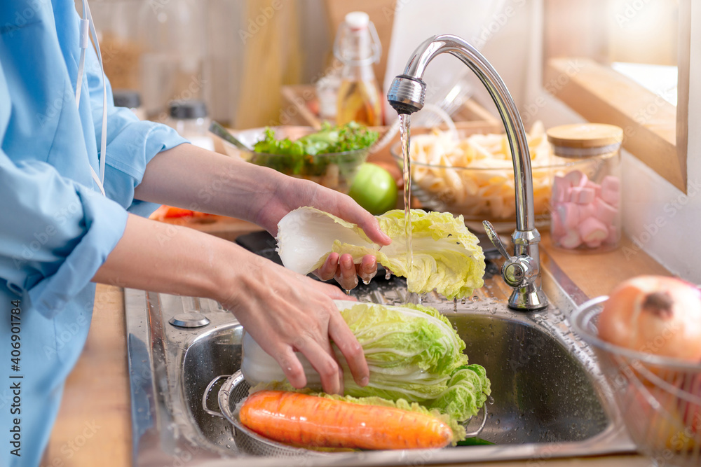 Woman's hands washing a fresh Vegetable to remove pesticides before cooking in kitchen under the tap
