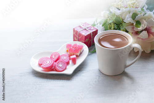 Sweet jelly in heart shaped plate for valentine's day, gift boxes,  bouquets and a cup of chocolate drink on wooden background