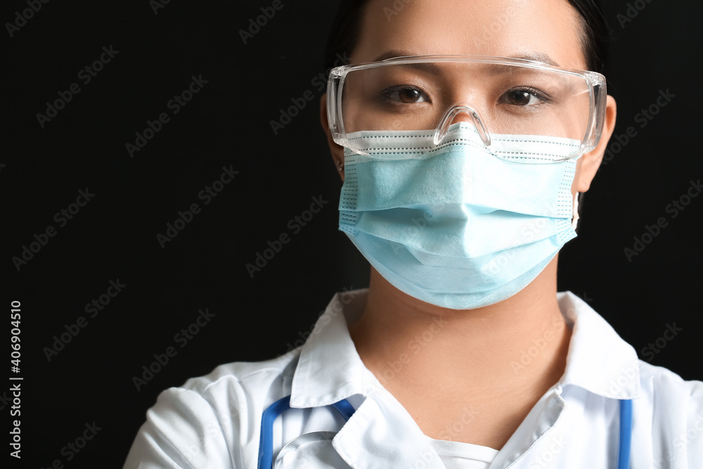 Portrait of female Asian doctor in medical mask on dark background Portrait of female Asian doctor in medical mask on dark background