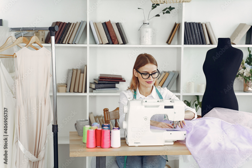 Obraz premium Woman use sewing machine. Designes sew cloth. Blonde in studio.