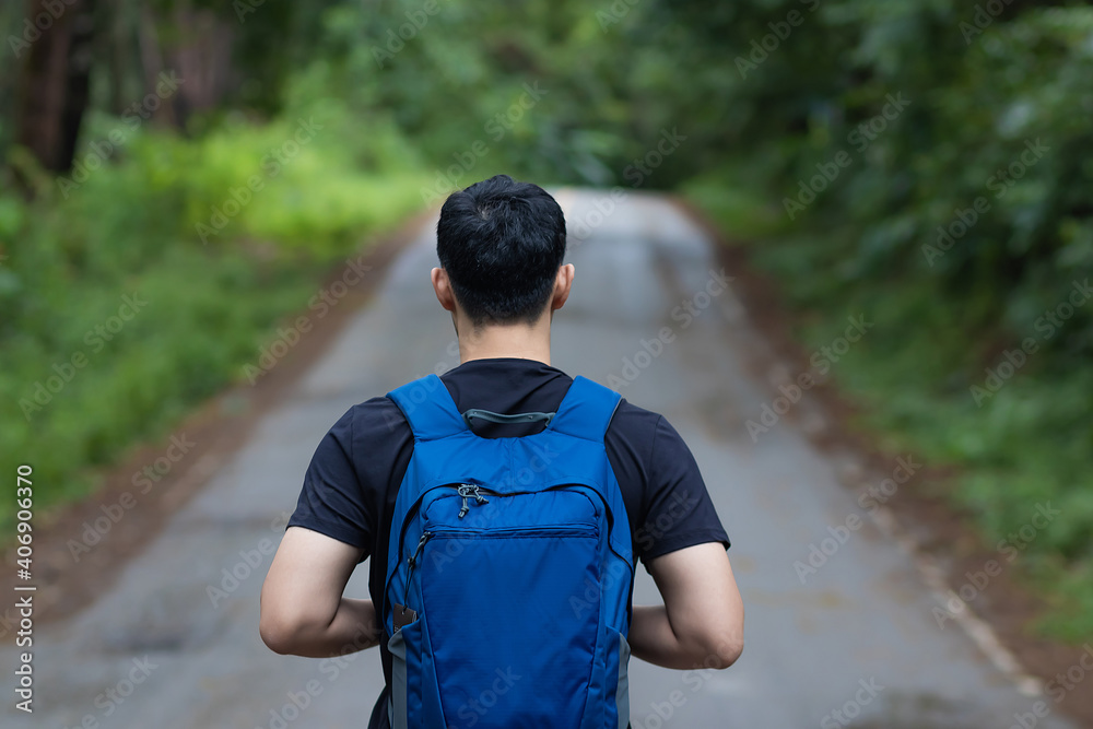 Rear view of young man with backpack hiking in forest. Rear view of young man with backpack hiking in forest.