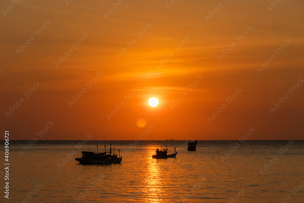 Sunset and fishing boat sailing along the sea.