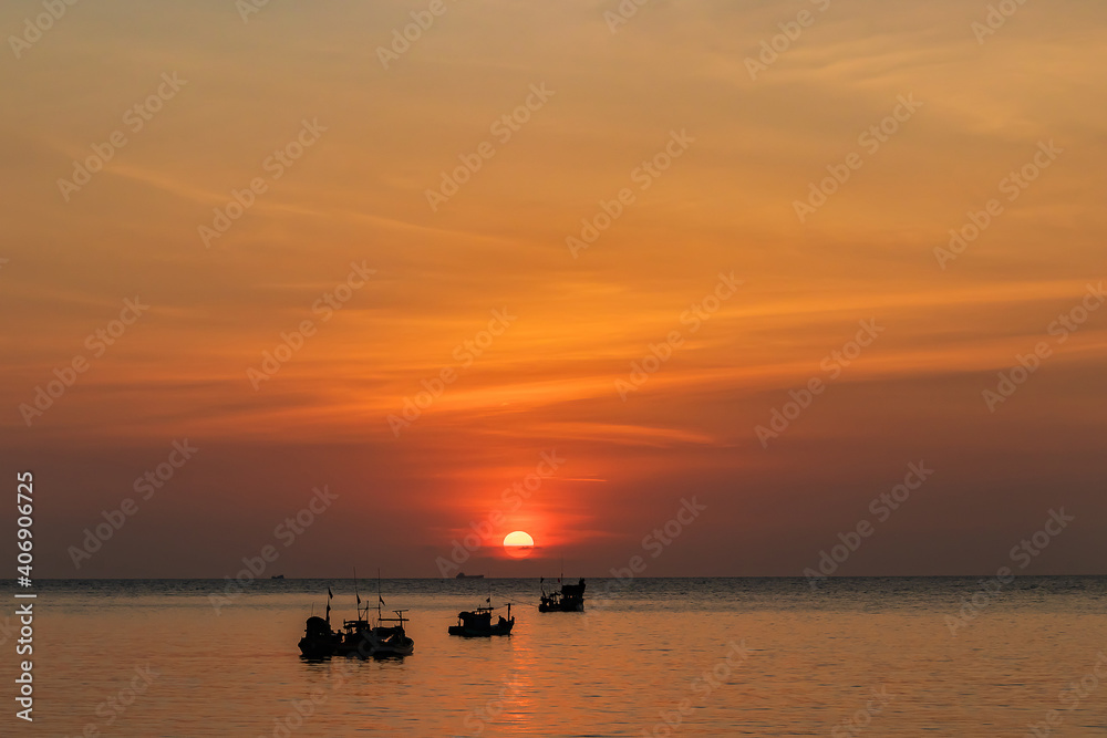 Beautiful sunset above the sea and fishing boat sailing along the sea.