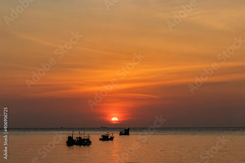 Beautiful sunset above the sea and fishing boat sailing along the sea.