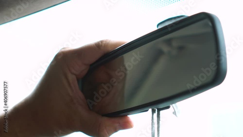 Man adjusting rearview mirror in car