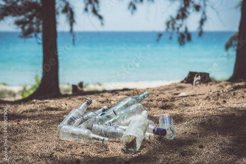 Close landfill old dirty transparent discarded empty glass alcohol drinks bottles trash on ground forest nature sea park. Alcoholism addiction problem bad habits, ecology issues environment pollution