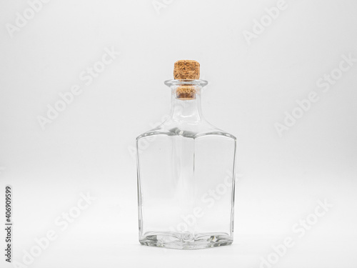 Empty glass bottle closed with cork cap isolated on a white background. Transparent square bottle. Front view of the vertical staying jar.