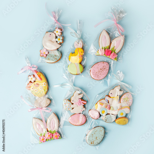 Easter cookies in personal package bag with pastel colored icing on blue background. Happy spring holiday, set of sweet gifts for anniversary, cute gingerbread