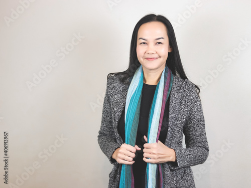  Asian business  woman with long black hair, wearing scarf  and winter coat, standing on white background smiling and looking at camera. winter portrait. photo