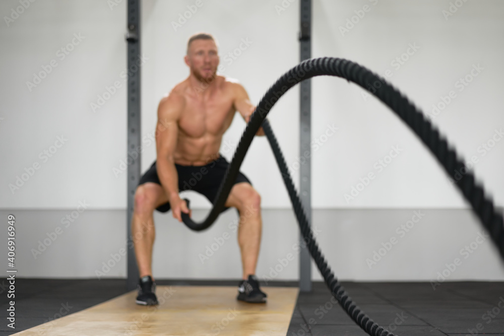 Unfocused unrecognizable man gym battle rope stamina training Athlete guy fitness exercising endurance indoor workout