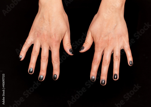 black nail polish with silver sequins on black background photo