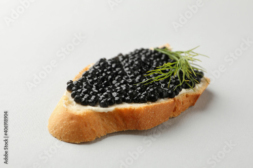 Sandwich with black caviar and dill on white background, close up