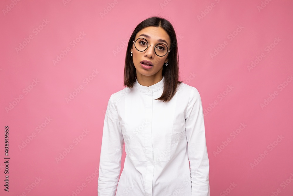 Photo shot of beautiful sad upset young brunette woman wearing casual clothes and stylish optical glasses isolated over colorful background looking at camera