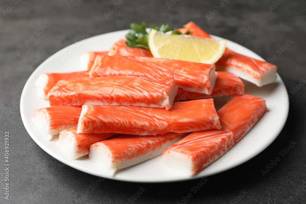 Plate of fresh crab sticks with lemon on grey table, closeup Plate of fresh crab sticks with lemon on grey table, closeup