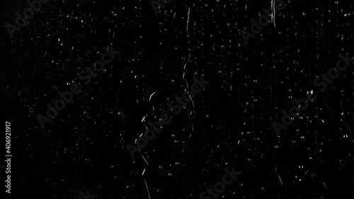Slow motion shooting of rainy drops on glass black background