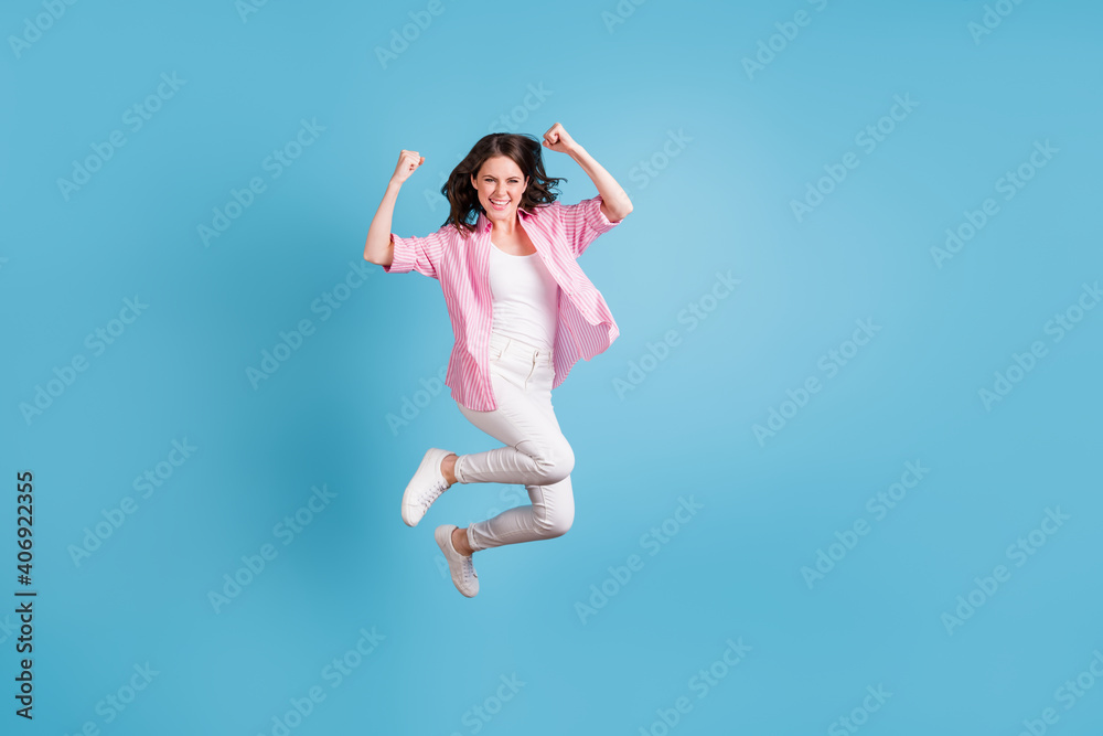 Full body portrait of astonished person jump raise fists up triumph lucky isolated on blue color background Full body portrait of astonished person jump raise fists up triumph lucky isolated on blue color background