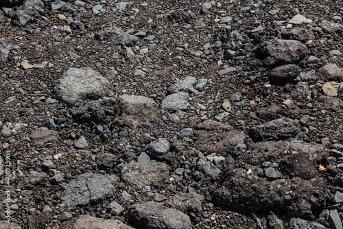 Broken road covered with old asphalt mixed with stones.