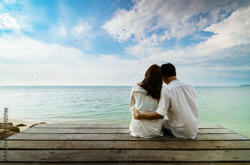 happy young couple sitting on wood bridge and sea beach at Koh MunNork Island, Rayong, Thailand