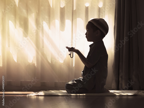 Silhouette image of Muslim pre school kid pray to God (Doing  Dua or supplication).Concept of Muslim Kid praying. photo