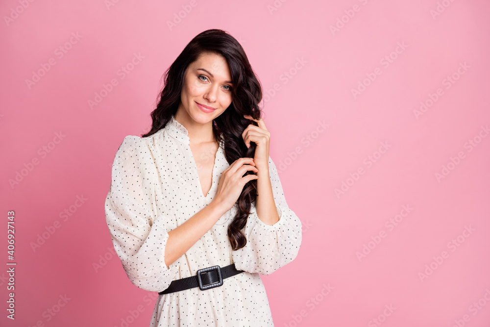 Photo portrait of dreamy girl touching silky brunette hair smiling isolated pastel pink color background with blank space