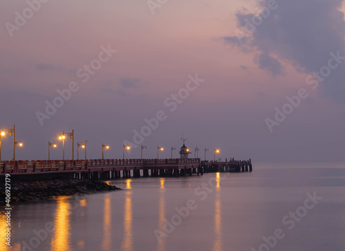 Background of the bridge, stretched into the sea, twilight in the morning, beautiful colors, sky wallpapers and lighthouse. A light reflecting into the sea © suththirat