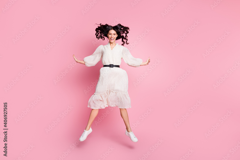 Full length body size photo of carefree playful woman in white dress jumping smiling isolated pastel pink color background Full length body size photo of carefree playful woman in white dress jumping smiling isolated pastel pink color background